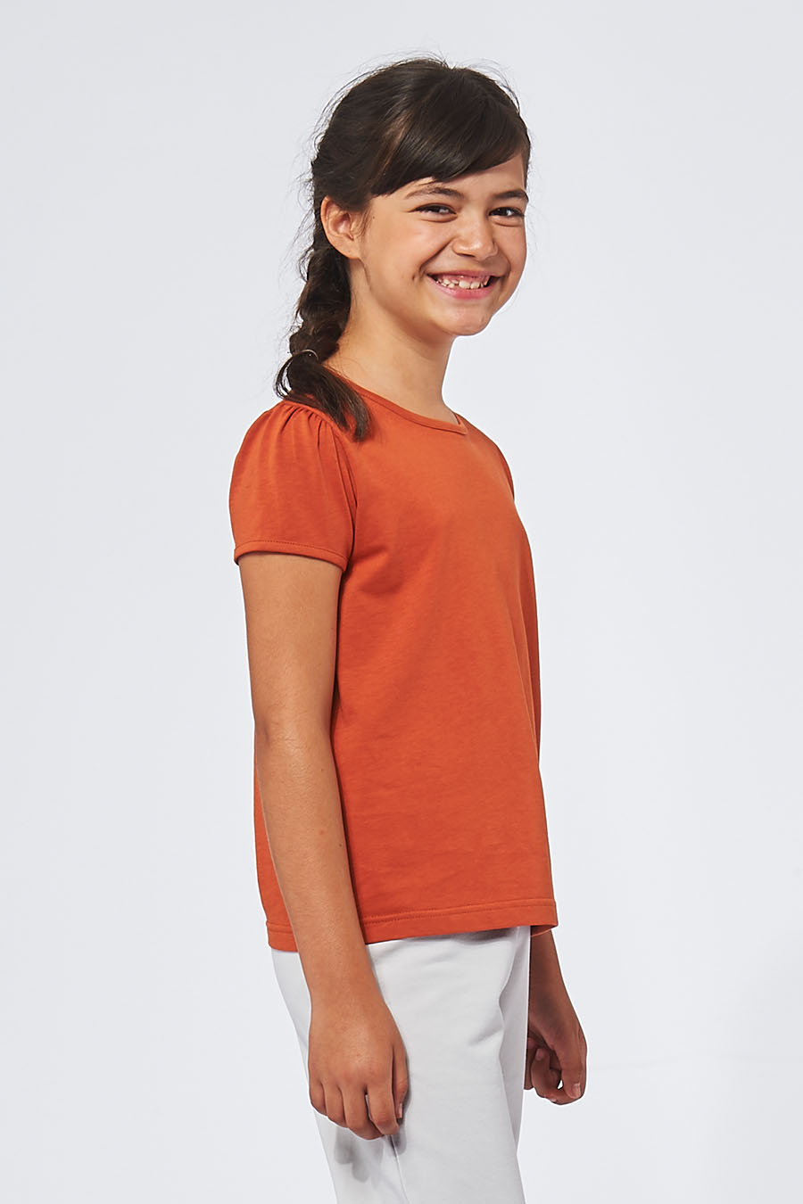 Tee-shirt made in France en coton bio RAFFAELLA brique fille de profil qui sourit - FIL ROUGE